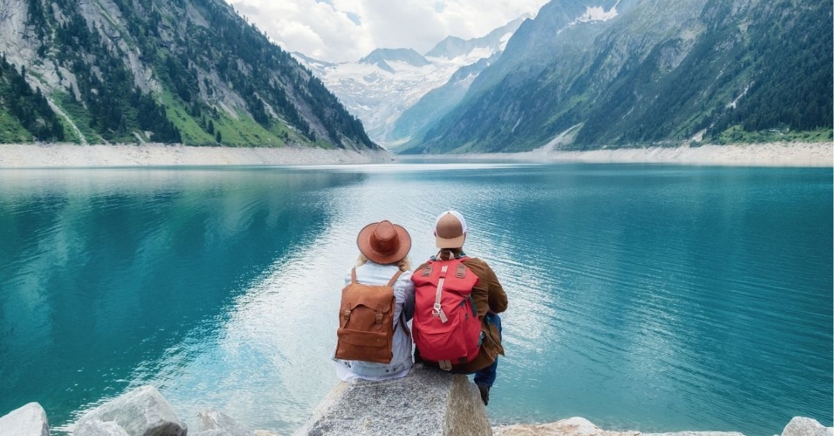 Travelers couple look at the mountain lake. Travel and active life concept with team.