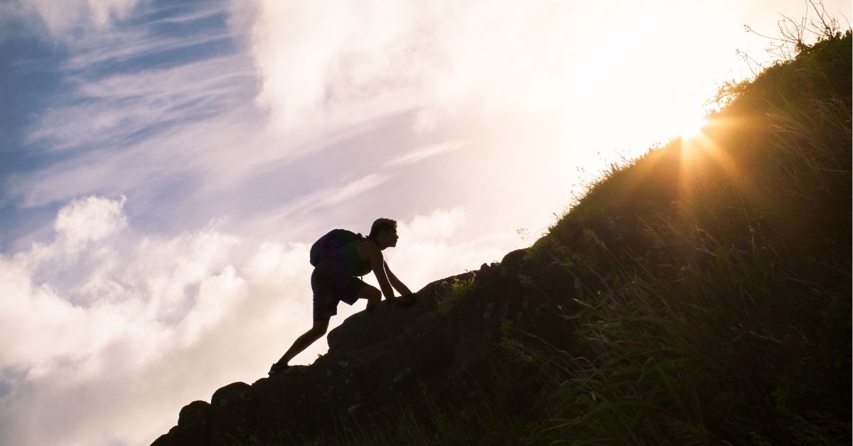 Young man climbing up a mountain. Self improvement and life goals concept. 