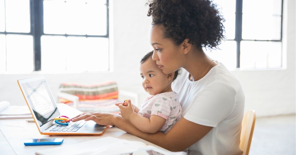 Mother working from home with daughter sitting on her lap 