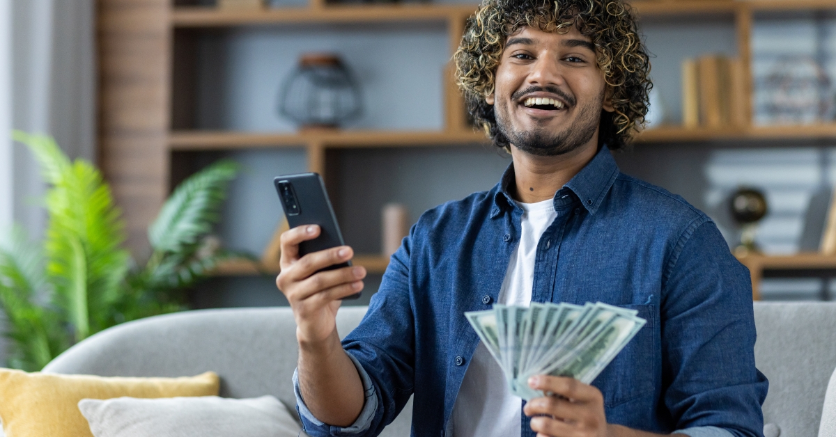 holding cash in one hand and a smartphone 