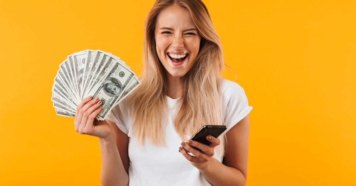 excited young blonde girl holding cash