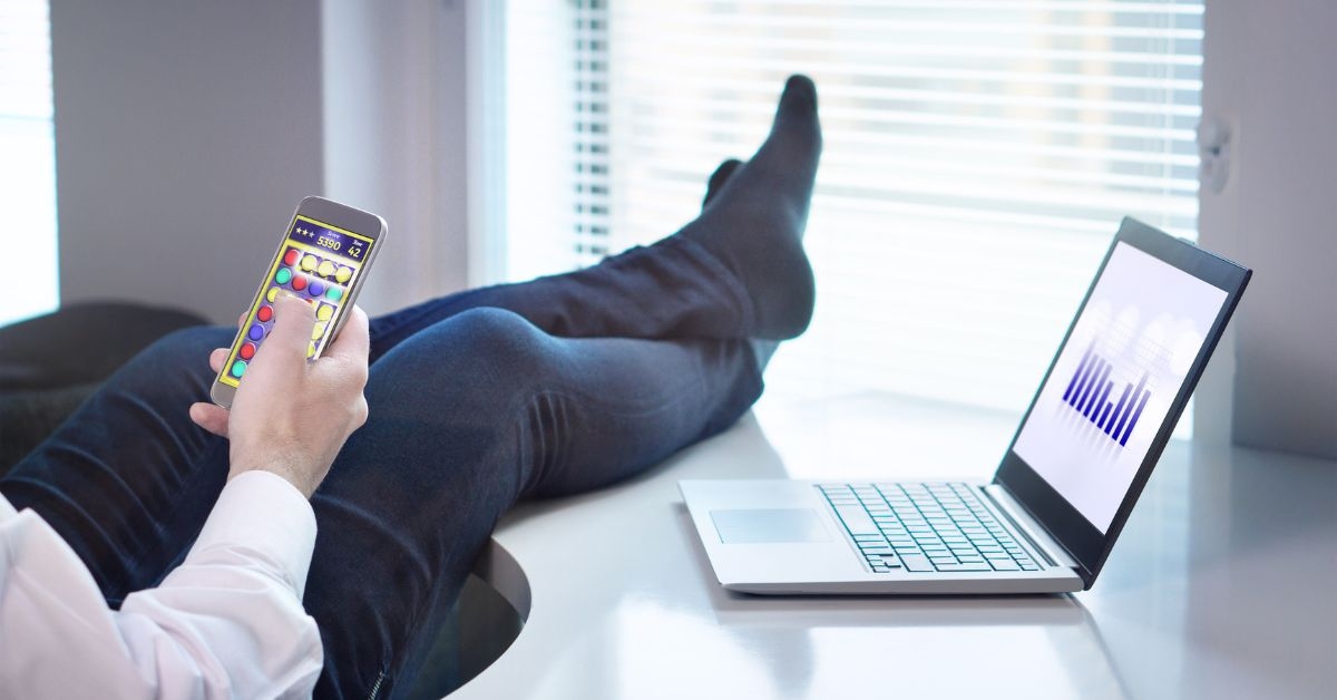 man avoiding work playing on phone