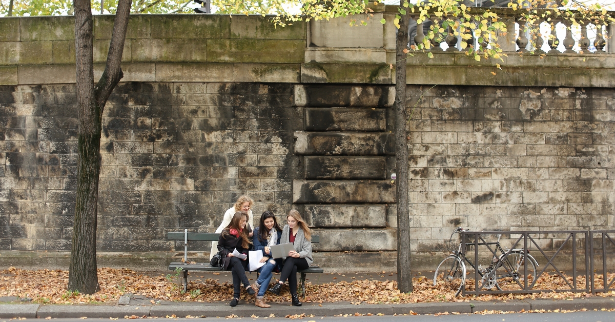 female students sitting on bench with teacher