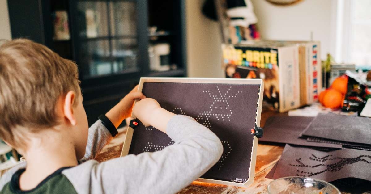 young boy playing lite brite