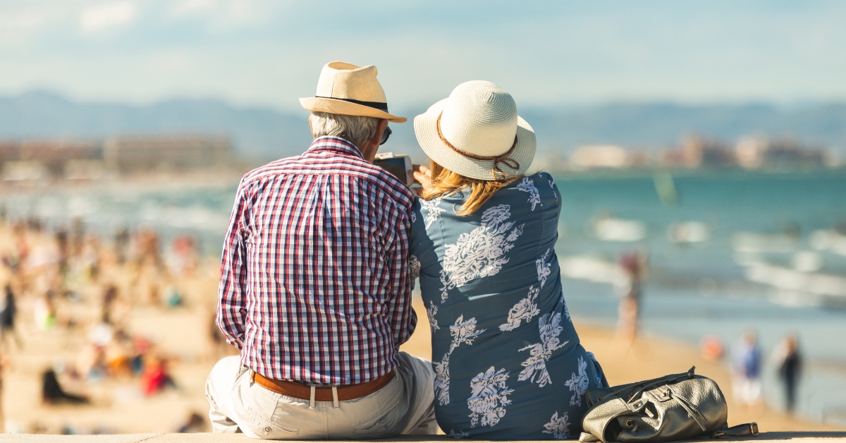 couple sitting on the wall facing at the beach
