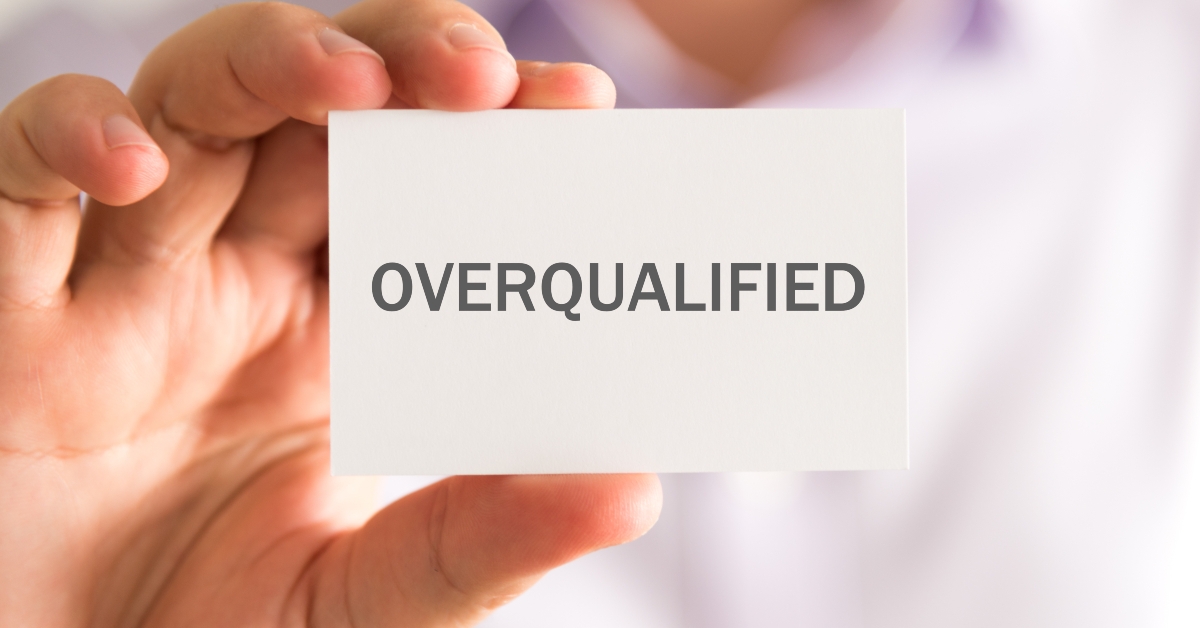 businessman holding card with overqualified message