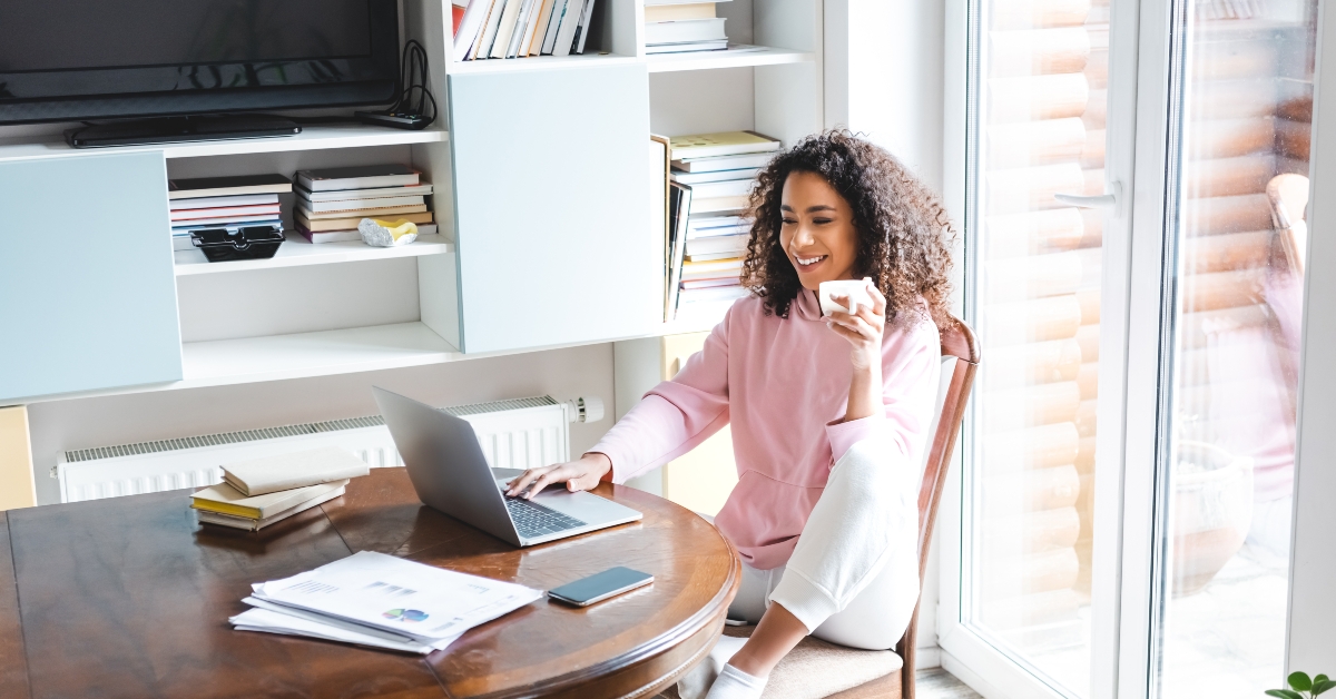female freelancer holding cup while using laptop