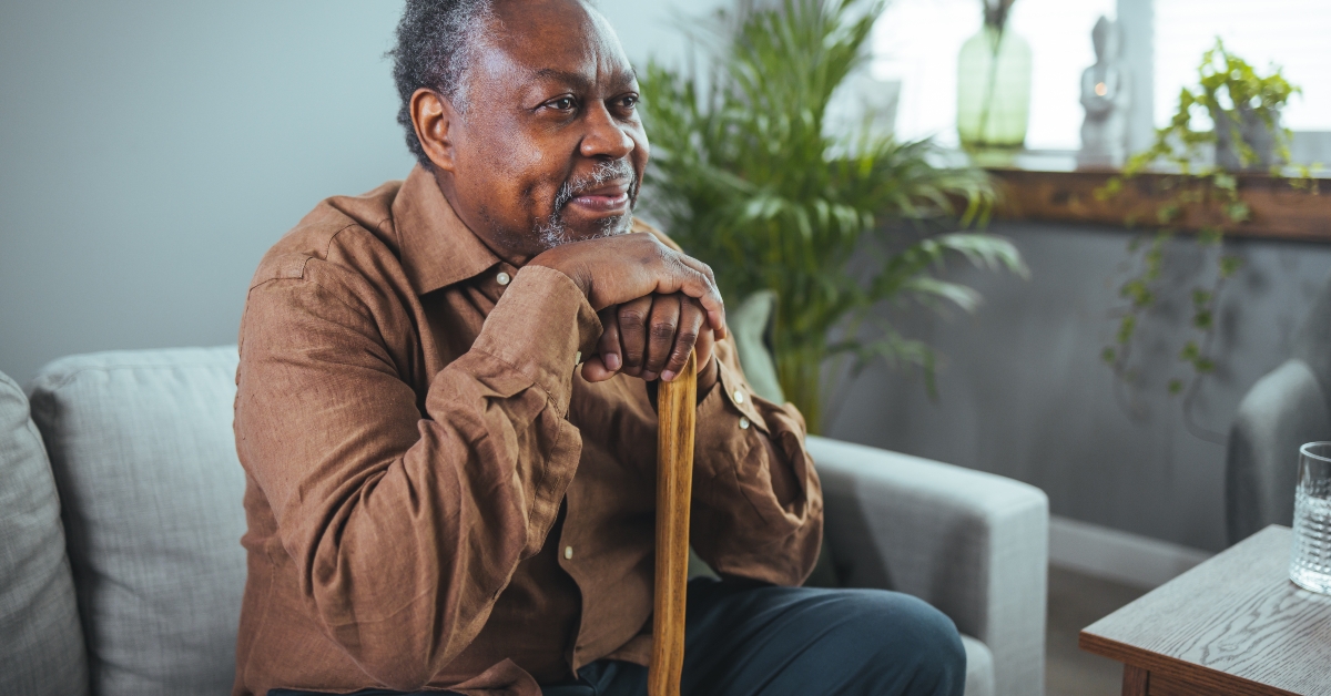 man sitting at home with walking stock and smiling