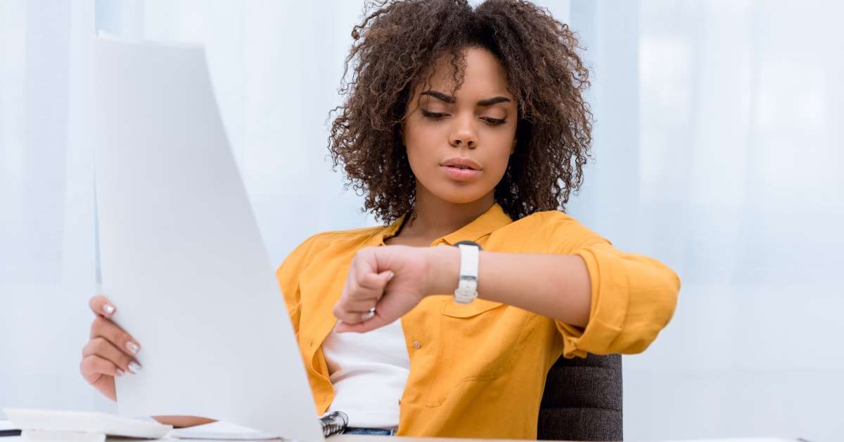 woman working at office and looking at watch