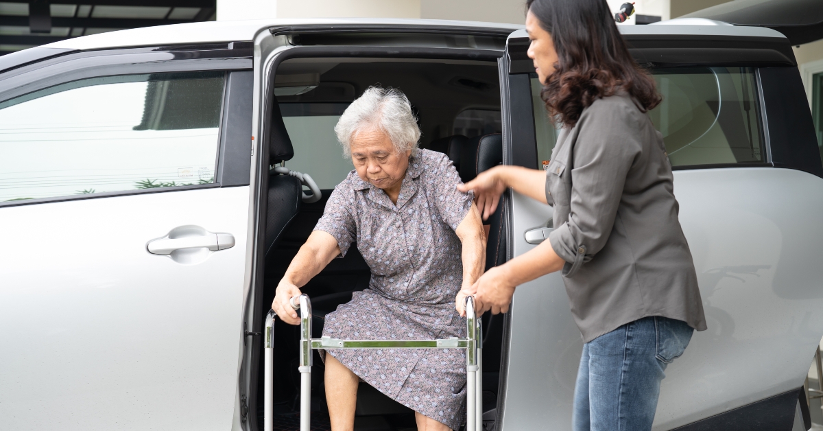 woman helping Asian senior to walker