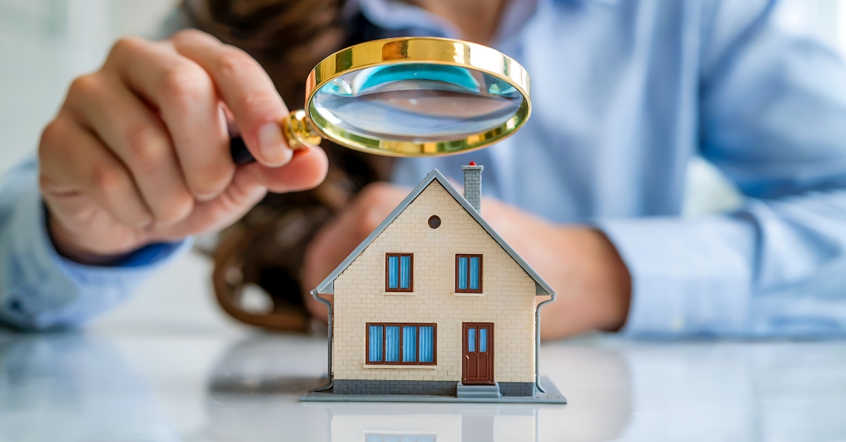 Woman inspecting a model house with a magnifying glass