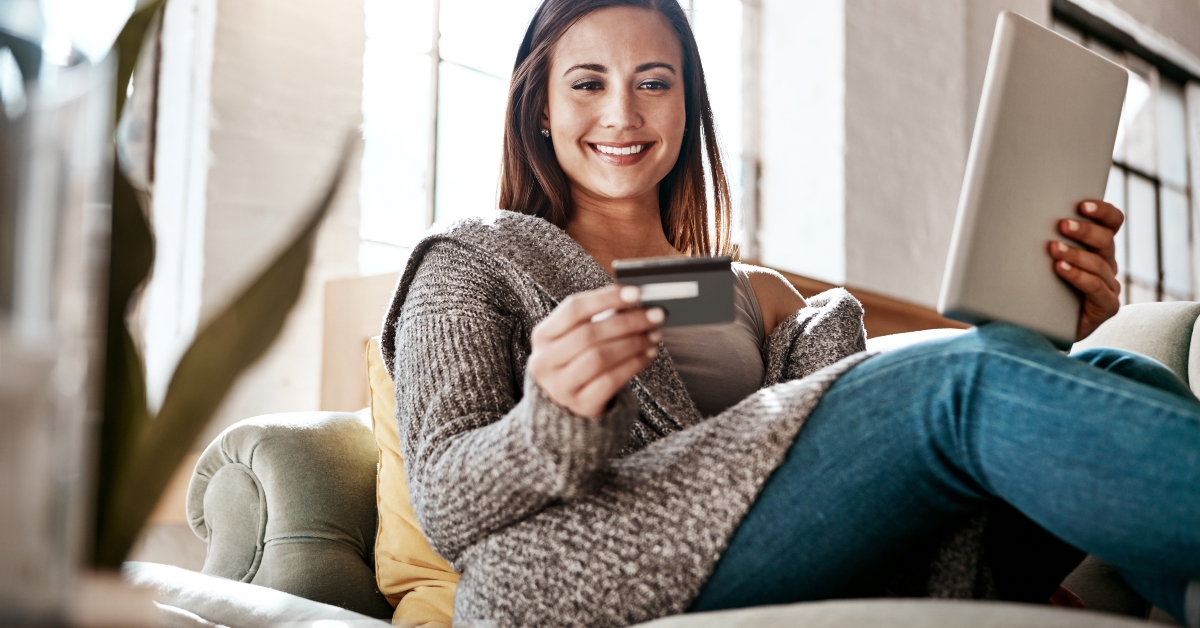 woman holding credit card while using tablet