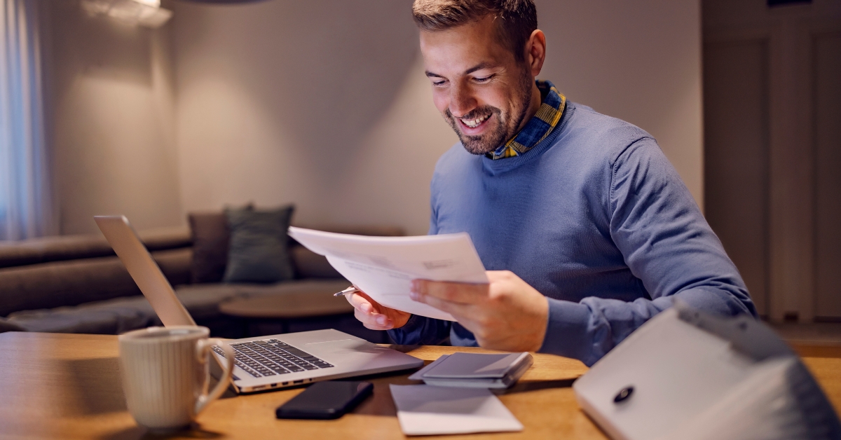 happy man holding bills and calculating budget