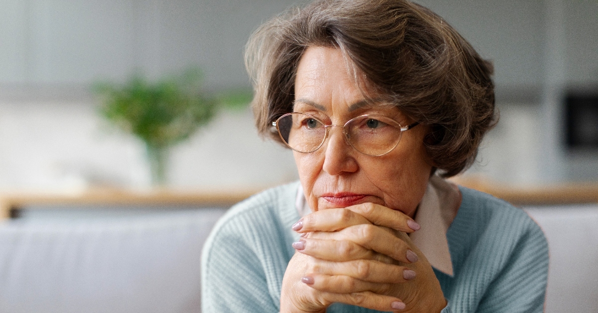 Older woman with hands crossed under her face looking worried