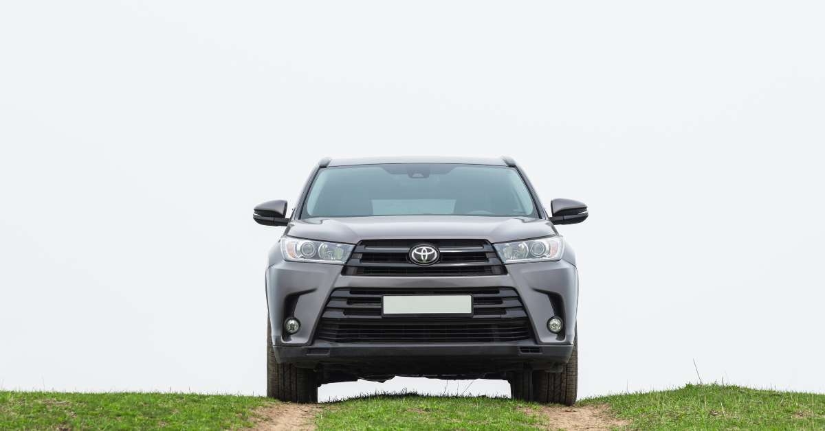 toyota highlander stands on top of a green hill