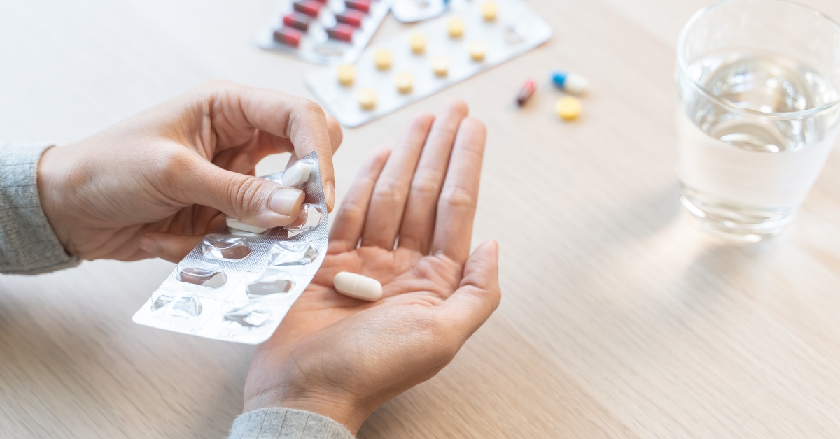 Close-Up Hands Holding Medication and Water Glass