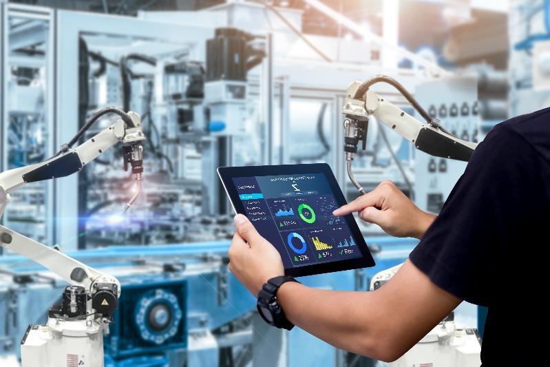 Hands holding tablet on blurred automation machine as background