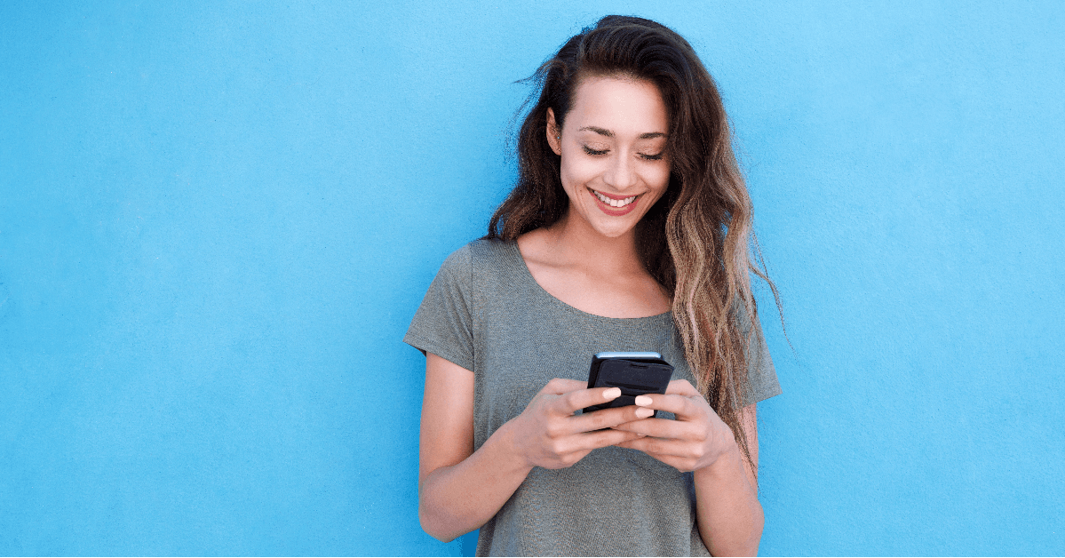 young smiling woman using mobile phone against blue background