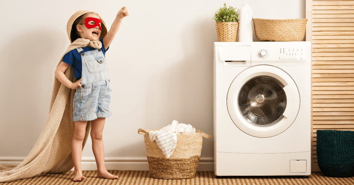 boy in cape and mask doing laundry