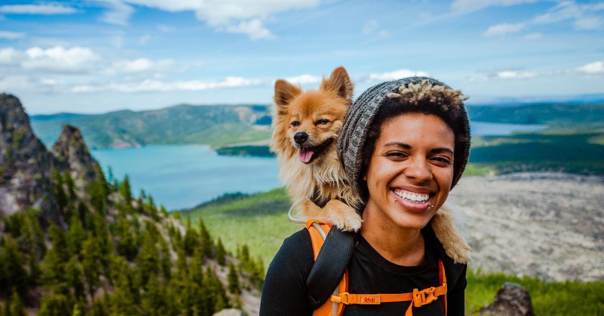 girl hiking with dog in backpack