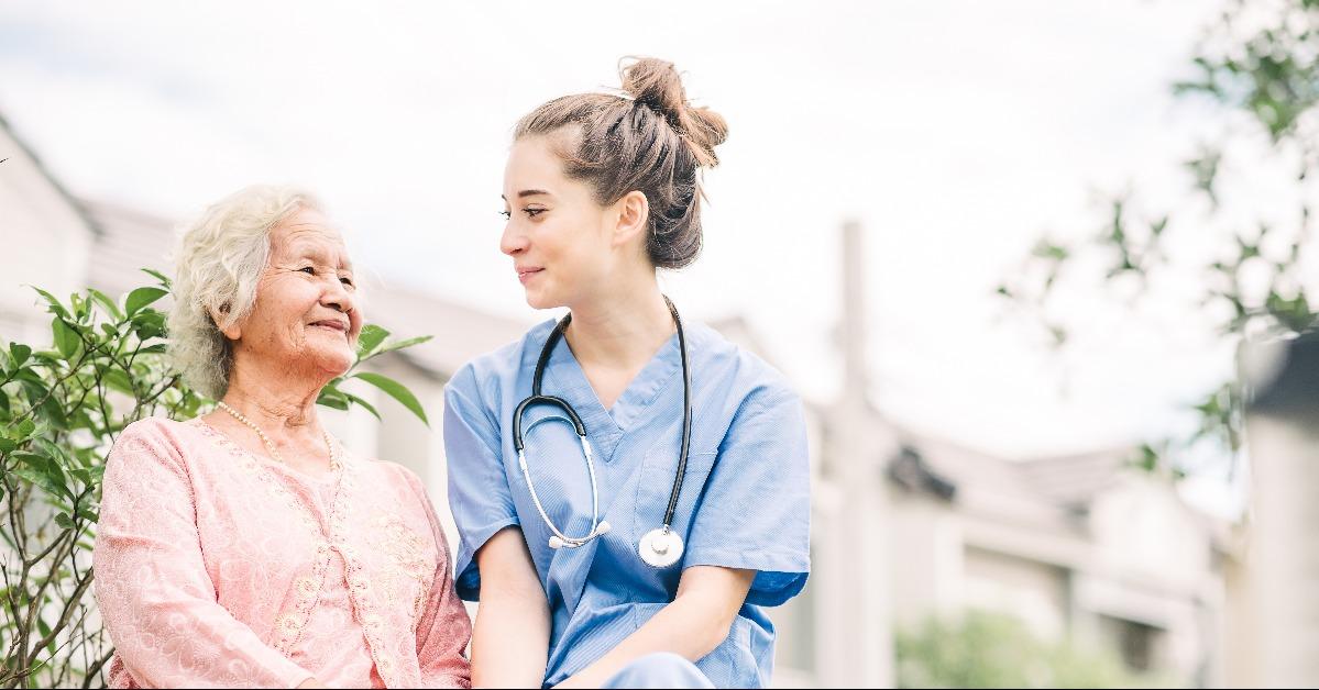 caregiver holding hand of happy elderly woman