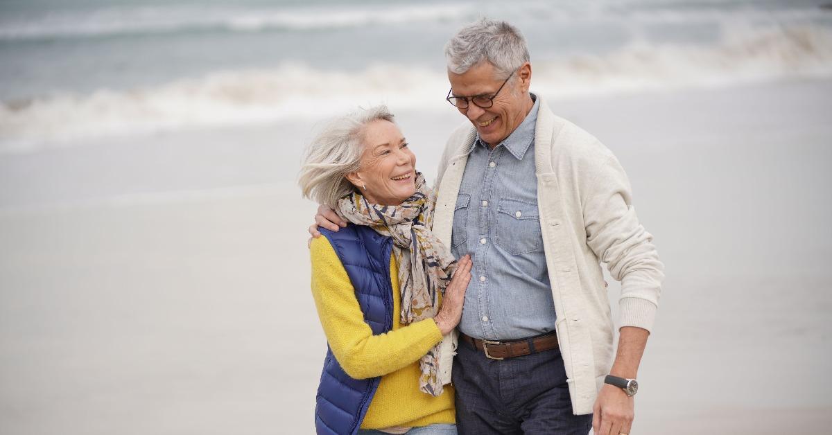happy senior couple walking together on the beach