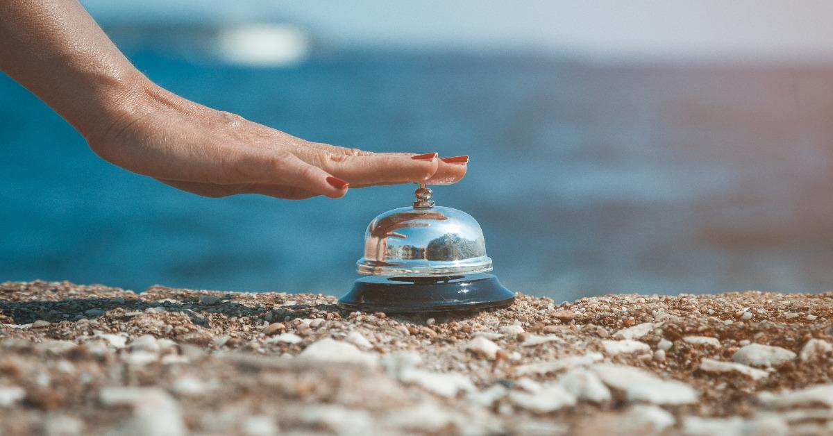 female hand ringing service bell against the ocean background