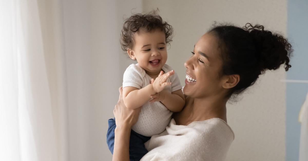 smiling young african American mom hold in hands happy baby