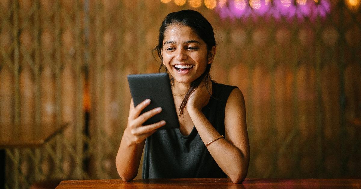 young indian woman sitting at a cafe enjoying reading a kindle