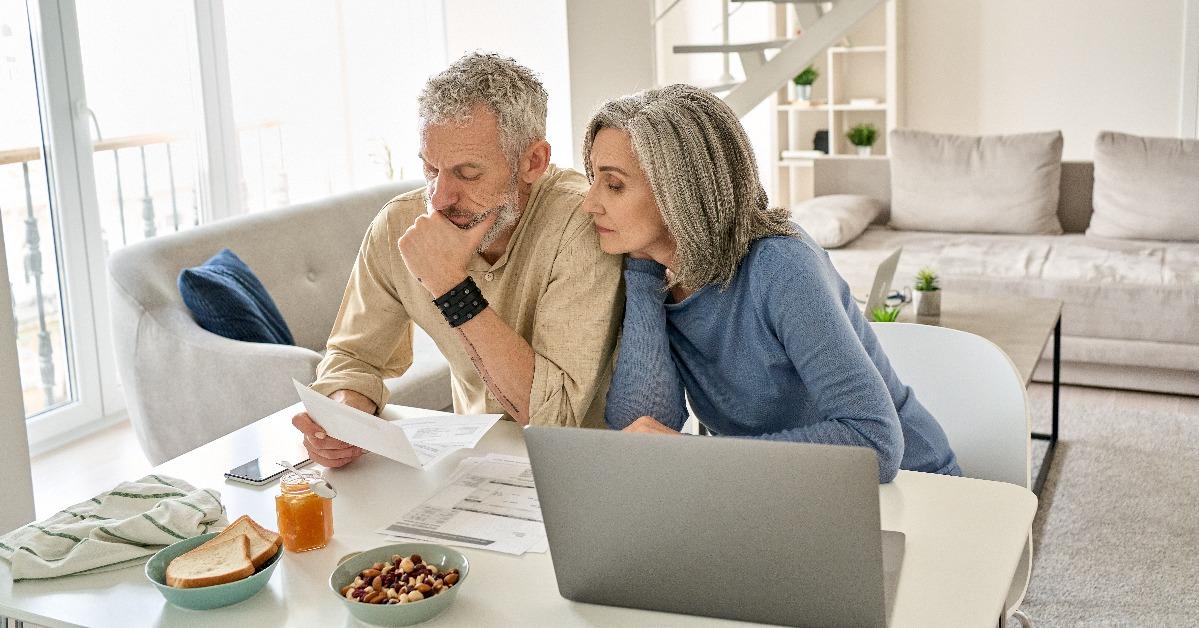 worried old senior couple checking bank documents at home