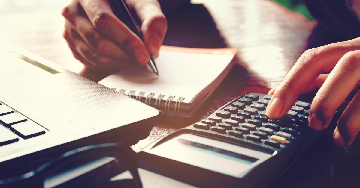 close up woman hand using calculator and writing make note with