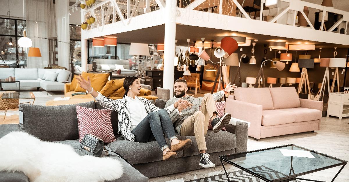 cheerful couple behaving childishly in furniture showroom