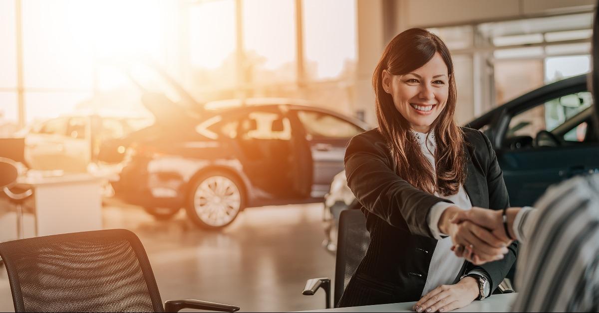 client shaking hands with car dealer in showroom