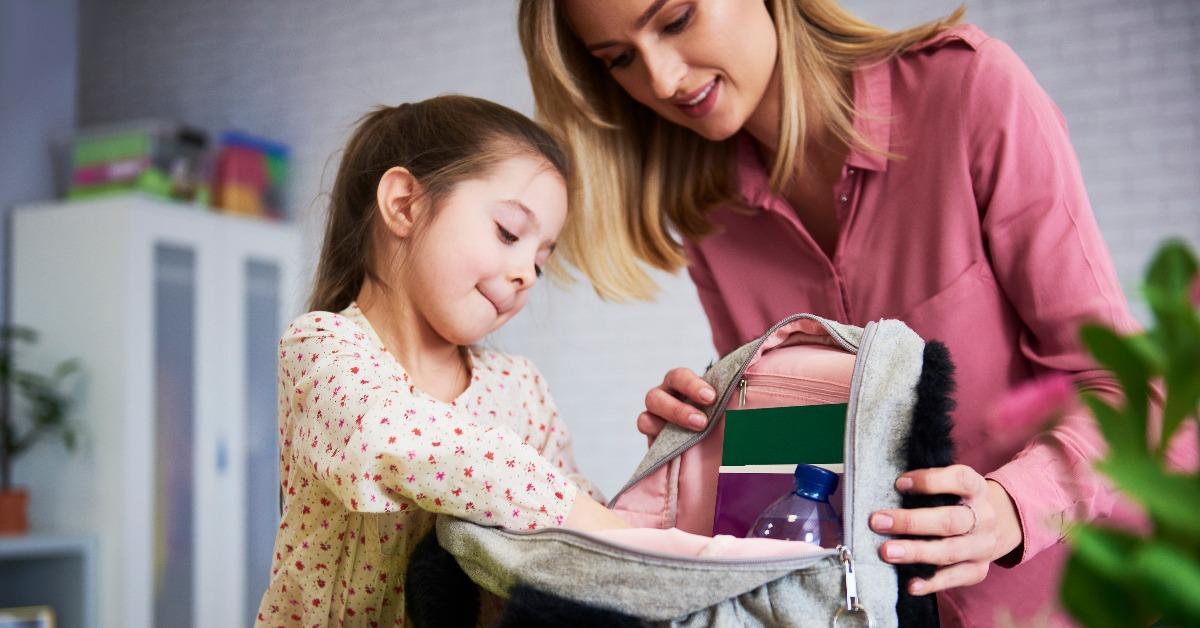 young mom and daughter packing backpack for the school