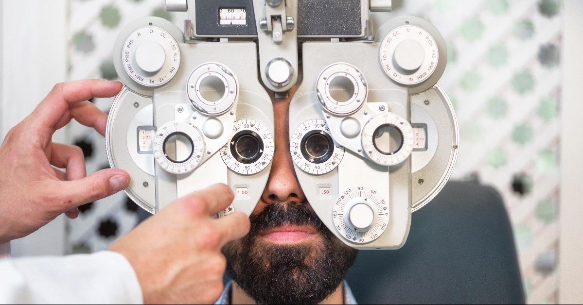 optometrist doing sight testing for male patient in clinic