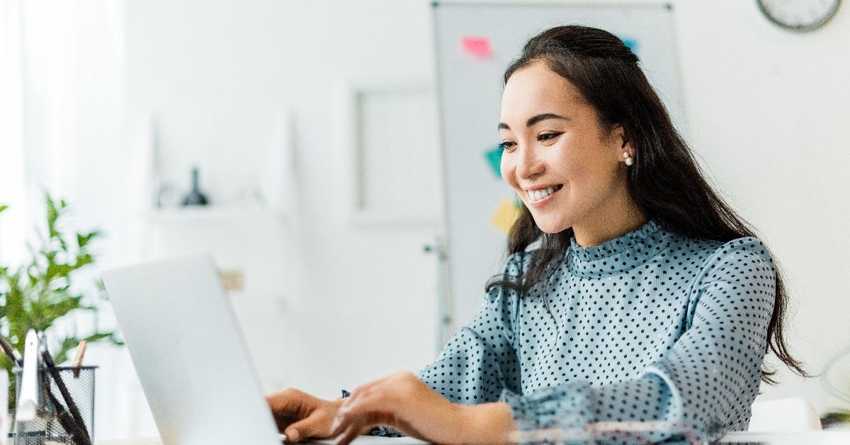  asian businesswoman sitting at desk and using laptop in office
