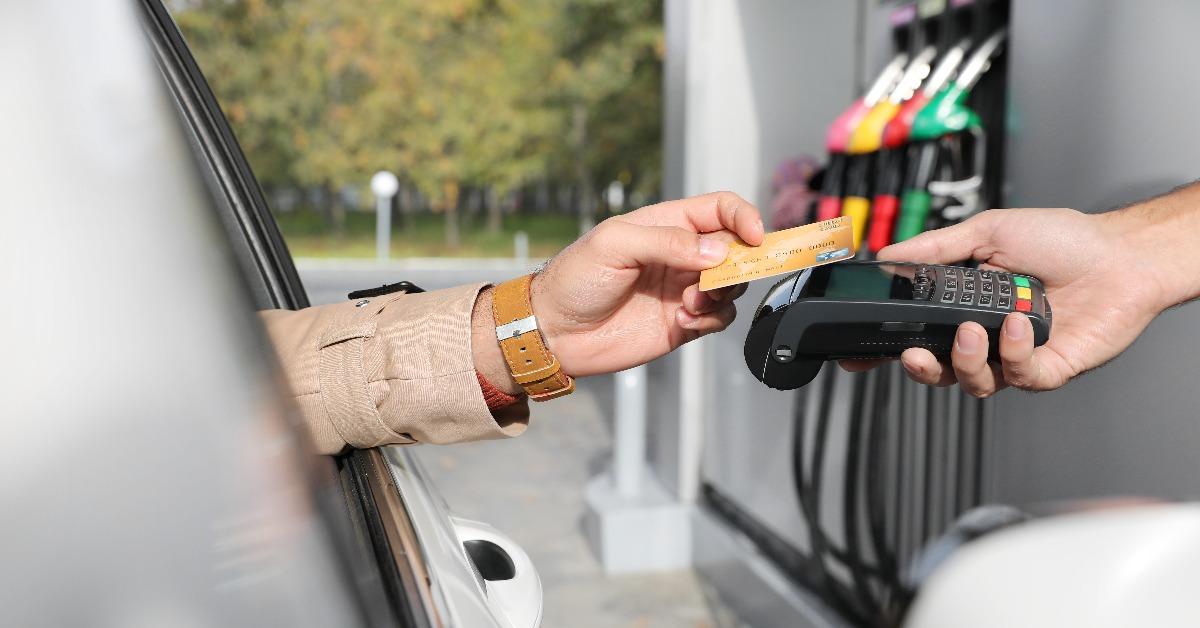 man sitting in car and paying with credit card at gas station