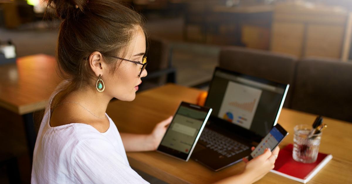 mixed race woman in glasses working with multiple electronic internet devices