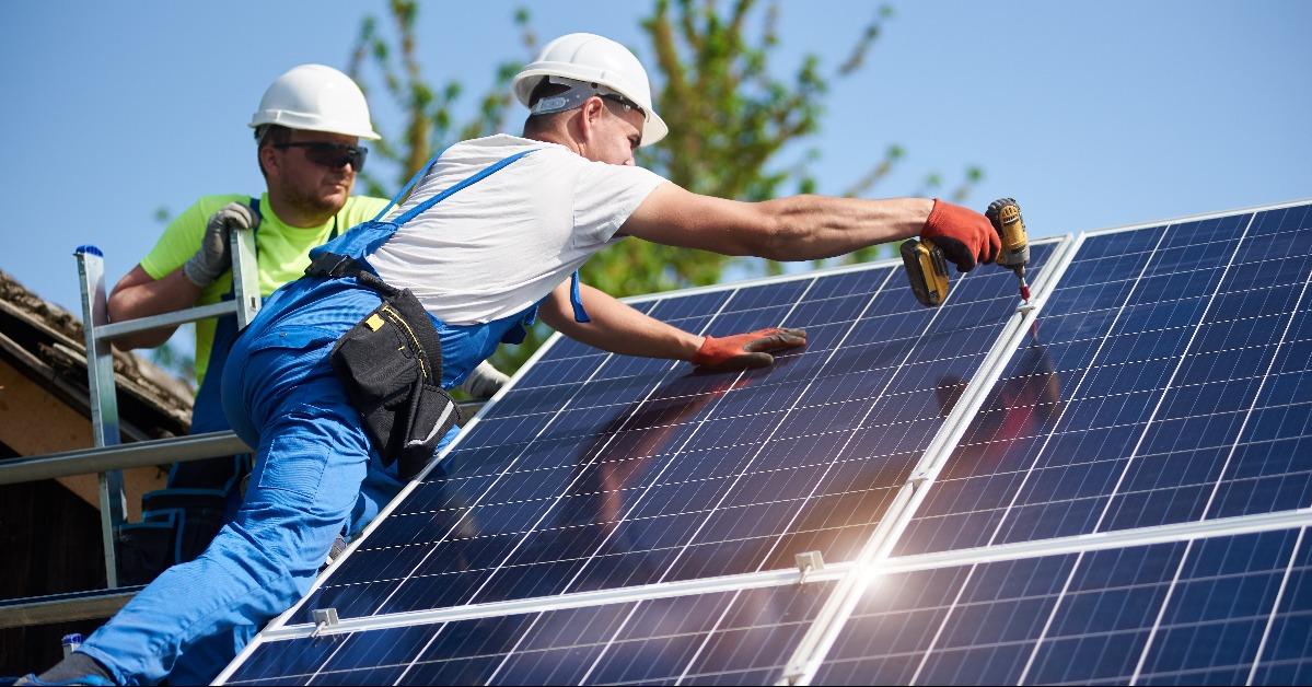technicians installing heavy solar photo voltaic panels to high steel platform