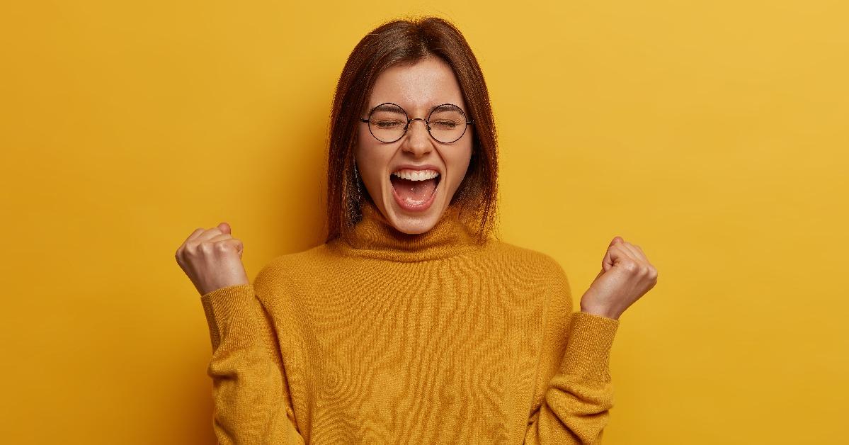  brunette young lady clenches two fists celebrates success 
