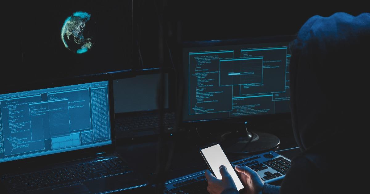 hacker in hood working at laptop and mobile phone
