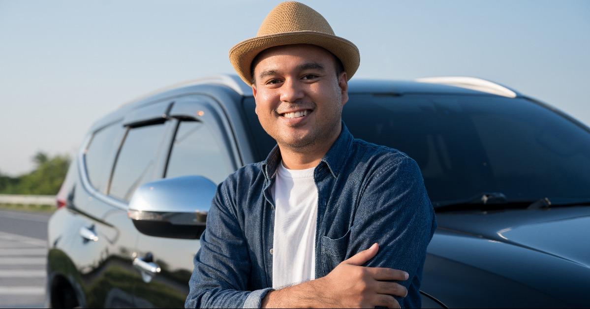 man standing with arm crossed in front of the car