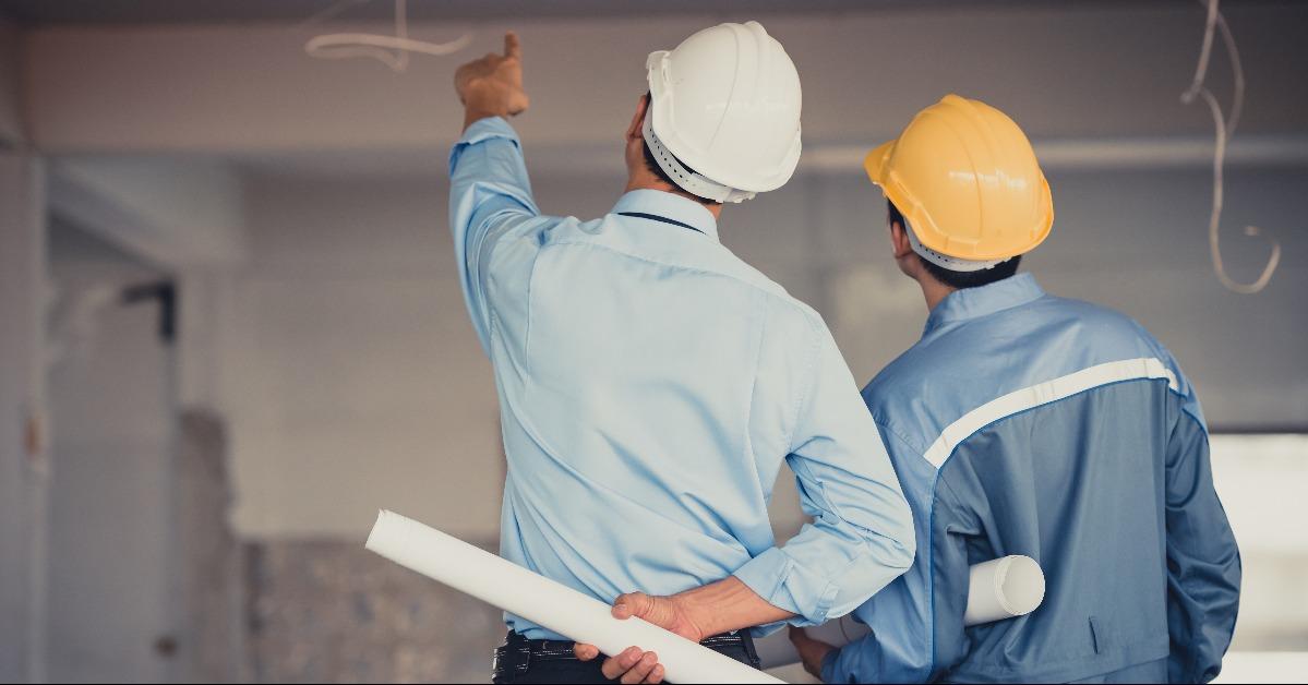 engineer team with hard hat and blueprint talking together