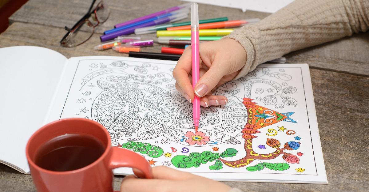 Woman coloring an adult coloring book and drinking tea