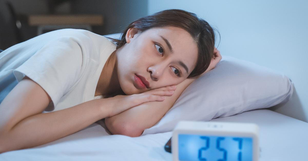 asian woman with open eyes while lying on the bed