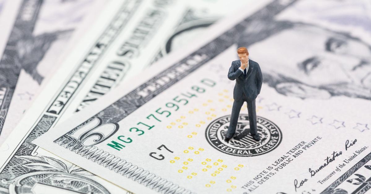 Miniature businessman leader standing on US Federal Reserve emblem 