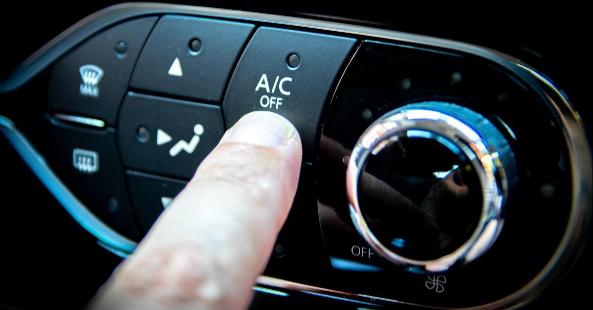 pressing the air conditioning button on the dashboard of a car