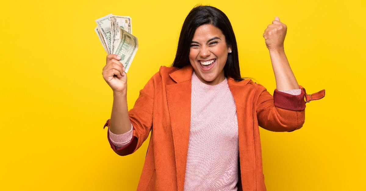 Young Colombian girl over yellow wall taking a lot of money