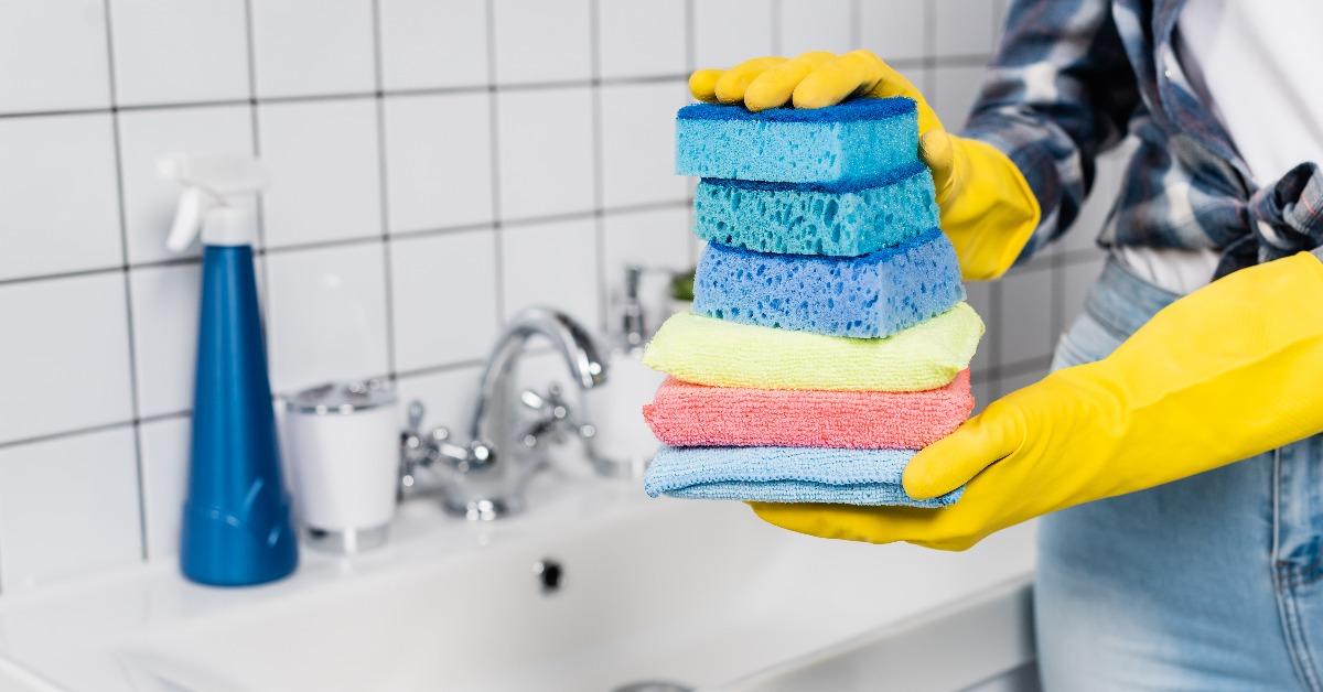 woman in rubber gloves holding colorful sponges