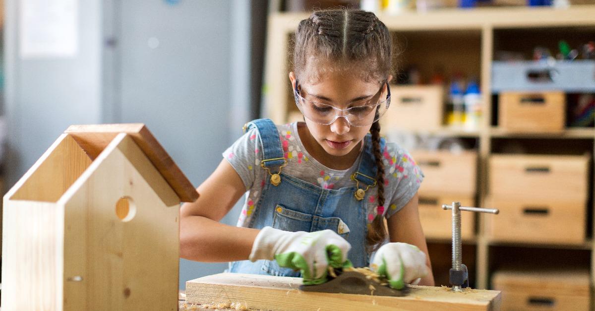 Girl building birdhouse in garage